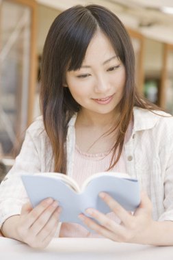 Kafede kitap okuyan güzel bir Japon kadın.