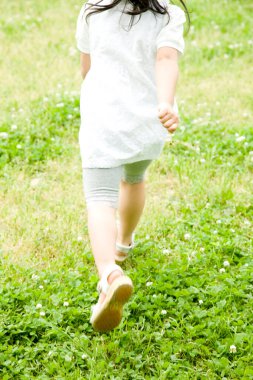 Parkta koşan küçük kızın arka görüntüsü