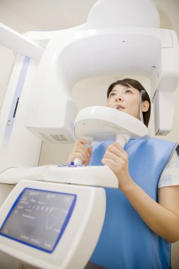 Genç Asyalı kadın dişlerinin röntgenini çekiyor.