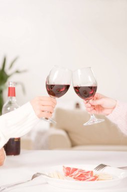 Yakın plan. Evlerinde kırmızı şarap bardakları olan iki genç insan..