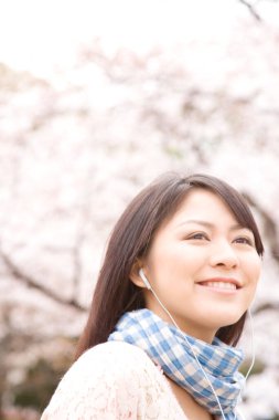 Sakura bahçesinde yürüyen güzel kadın, bulanık arka planda açık hava portresi. 