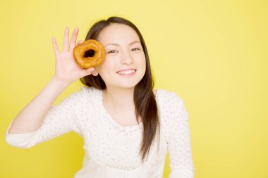 Genç Asyalı kadın donut gösteriyor. 