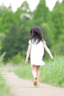 Gündüz vakti yeşil alanda koşan kız çocuğu 