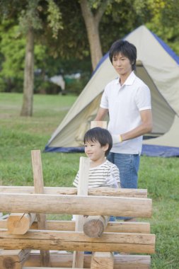 Genç bir aile küçük bir oyuncak ahşap ev inşa ediyor. 