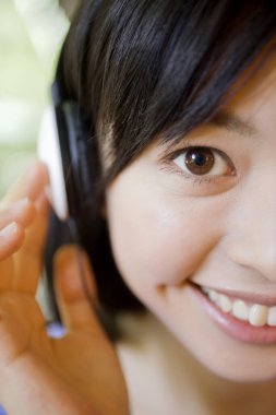 Kulaklıklı Asyalı kızın poirözelliğini kapat