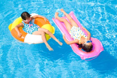 Şişme halkaların içinde yüzen iki küçük Asyalı kız. 