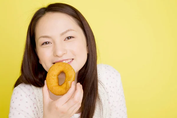 年轻的亚洲女人在吃甜甜圈 — 图库照片