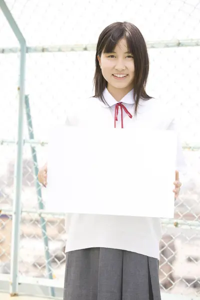 白い空白板を保持する美しい日本の女子高生の肖像画 — ストック写真