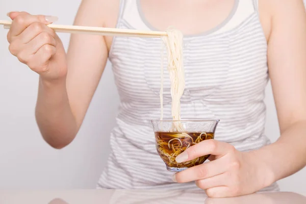 年轻女子用筷子吃面条 — 图库照片