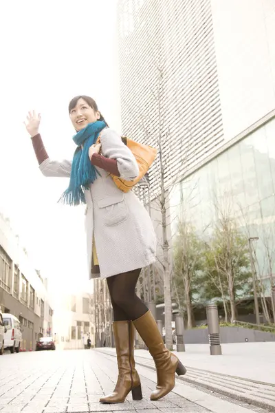 young woman waving hand  in city