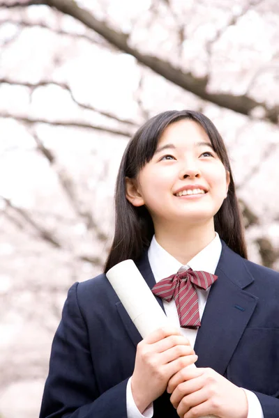 桜の木の背景に学校の制服で美しい日本の女の子 — ストック写真
