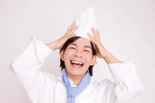 Sorridente Asiatico Uomo Bianco Uniforme Holding Mani Cappello — Foto Stock