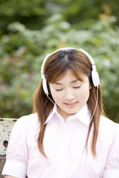 young japanese woman listening to music on headphones