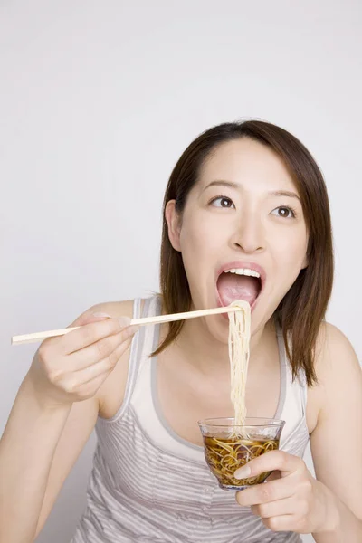若いアジアの女性は箸で麺を食べる — ストック写真