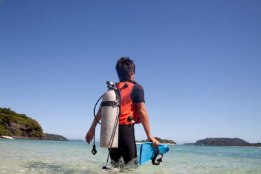 Deniz sahilinde yüzgeçleri, hava tankı ve kırmızı yeleği olan genç Asyalı dalışa hazır. 