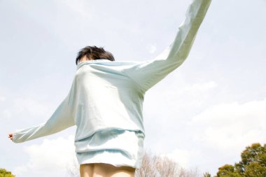 Kollarını açık havada, mavi gökyüzünün altında uzatan kişi