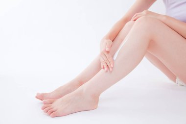 Genç bir kadın bacaklarına krem sürüyor.