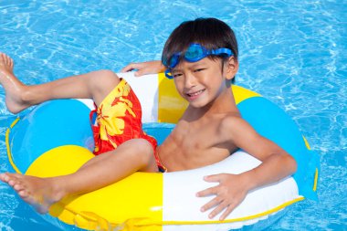 Mavi yüzme havuzunda şişirilebilir yüzüklü küçük şirin çocuk. 