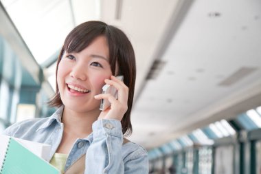 Üniversitede telefonla konuşan Asyalı genç kız öğrenci.