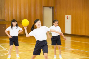 Asyalı çocuklar futbol topuyla egzersiz yapıyor.