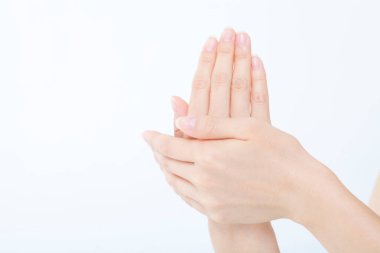 Kadın elleri beyaz arka planda krem sürüyor.