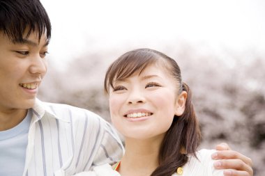 Daytime portrait of japanese couple walking at cherry garden