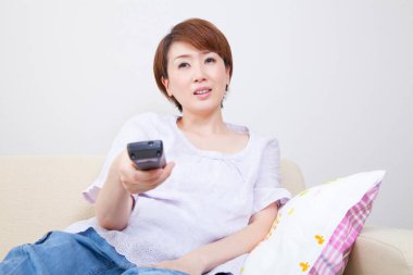 Evde uzaktan kumanda kullanan kadın 