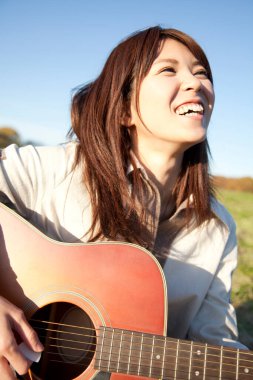Çimenlerde gitar çalan kadın