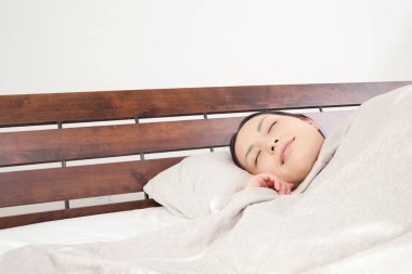 Güzel genç Asyalı kadın evde yatakta uyuyor.