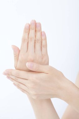 Kadın elleri beyaz arka planda krem sürüyor.