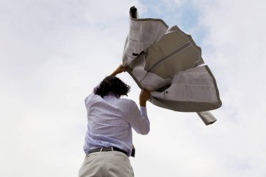 Elinde ceketi olan bir iş adamı gökyüzü arka planında