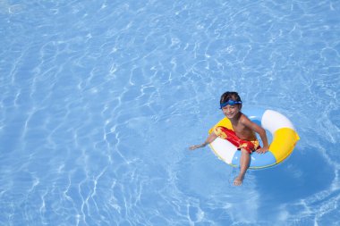 Mavi yüzme havuzunda şişirilebilir yüzüklü küçük şirin çocuk. 