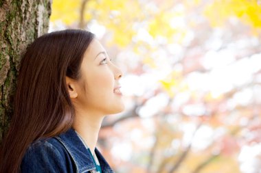 Güzel Asyalı kadın sonbahar parkında geziniyor.