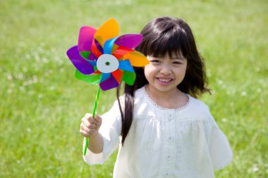 Güzel Asyalı kız renkli yel değirmeniyle oynuyor.