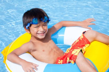 Mavi yüzme havuzunda şişirilebilir yüzüklü küçük şirin çocuk. 