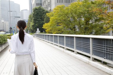 Şehre yürüyen iş kadınının arka görünüşü