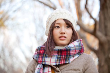 Genç güzel Asyalı kadın sonbahar parkında poz veriyor.