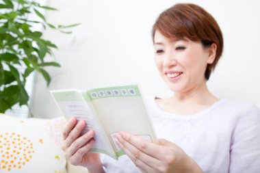 Asyalı kadın elinde bir kitap tutuyor. 