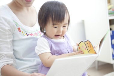 Küçük çocukla kitap okuyan bir kadın.