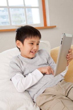 Asyalı çocuk evde video oyunu oynuyor. 