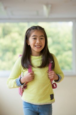 Okulun koridorunda sırt çantalı Asyalı bir kızın portresi.