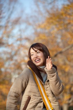 Genç güzel Asyalı kadın sonbahar parkında poz veriyor.