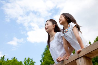 Genç bir Asyalı kadın ve küçük kızının yürüyüşe çıkmış portresi.