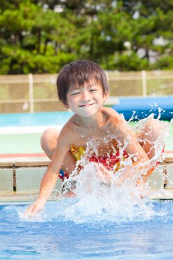 Mutlu Asyalı çocuk havuzda yüzüyor. 