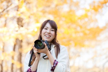 Sonbahar parkında fotoğraf çeken bir kadın.