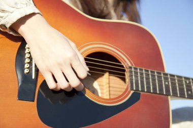 Dışarıda gitar tutan bir kadın.