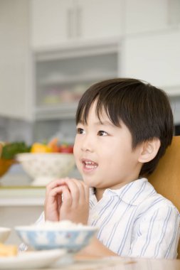 Evde yemek yiyen küçük şirin bir çocuğun portresi.