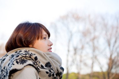 Genç güzel Asyalı kadın sonbahar parkında poz veriyor.