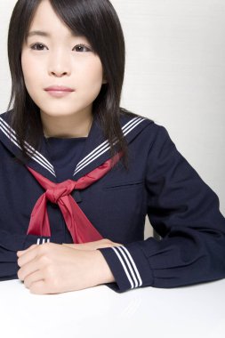 Asyalı üniformalı kız öğrenci çalışıyor. 