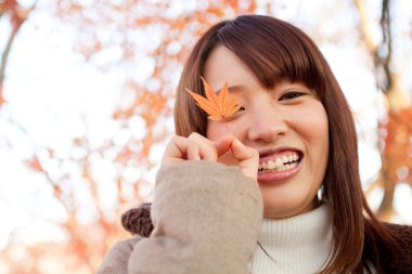 Genç güzel Asyalı kadın sonbahar parkında poz veriyor.